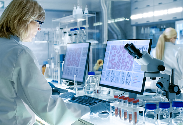 senior female scientist works with high tech equipment in a modern laboratory. her colleagues are working beside her.